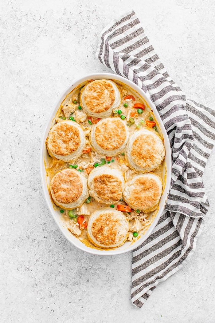 chicken pot pie with biscuits in a white casserole dish