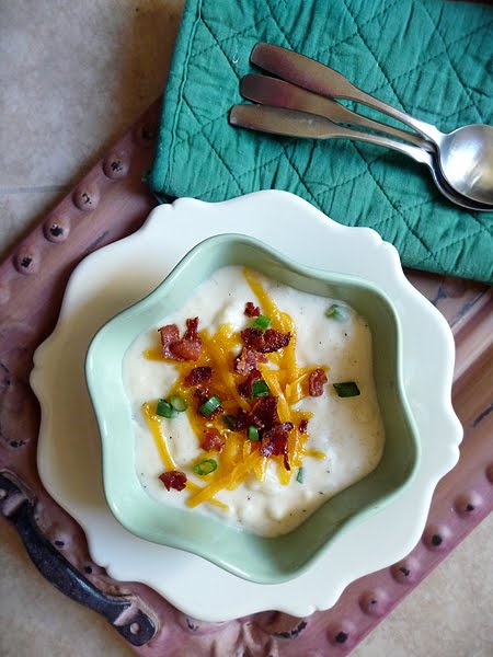 Overhead view of a bowl of loaded baked potato soup garnished with bacon, cheese, and green onions. 