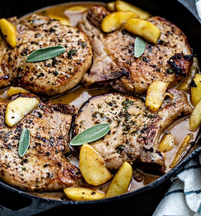 pork chops with sage in and apples in a cast iron skillet