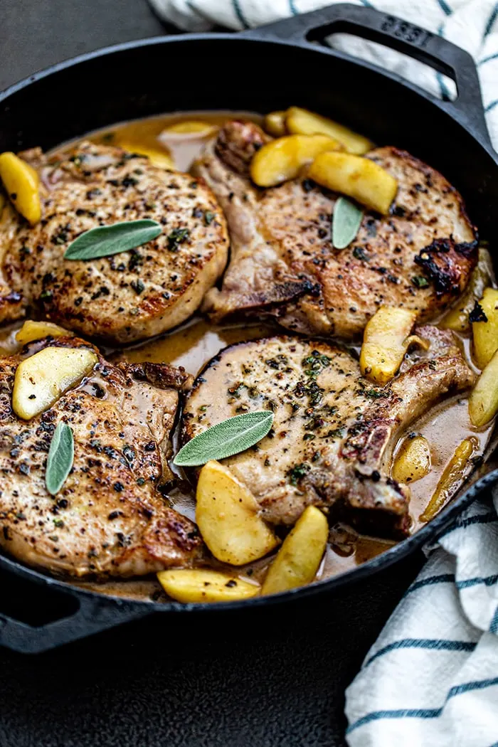 pork chops with sage in and apples in a cast iron skillet