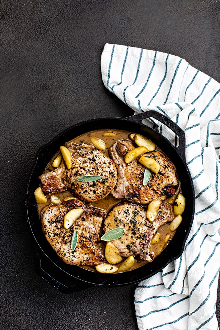 pork chops and apples in cast iron garnished with fresh sage