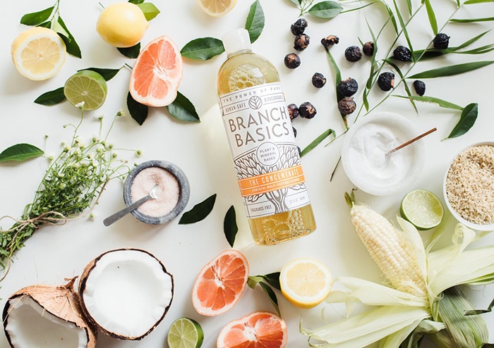 overhead shot of branch basics non toxic cleaners on a white counter with citrus fruits (includes a branch basics coupon code in the post)