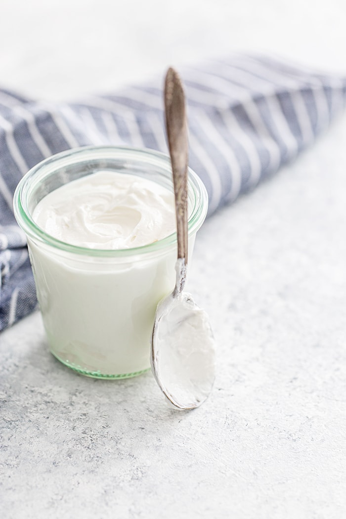 a photo of a jar of sour cream with a spoon to be used as a buttermilk substitute