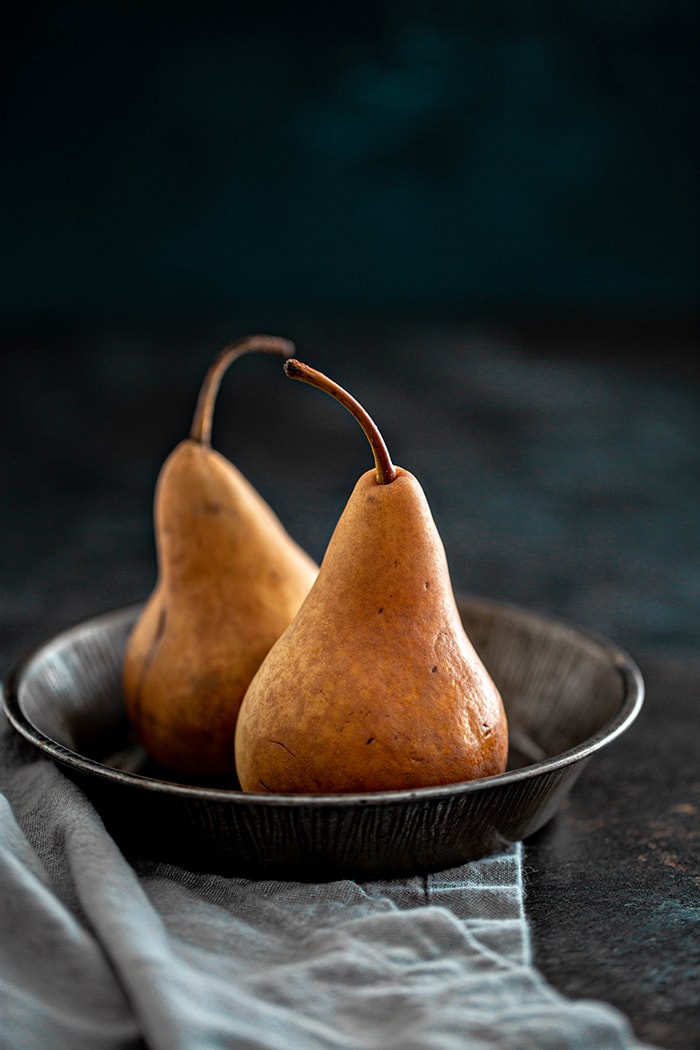 pears on a dark background to use to make these pomegranate and pear crostini appetizers