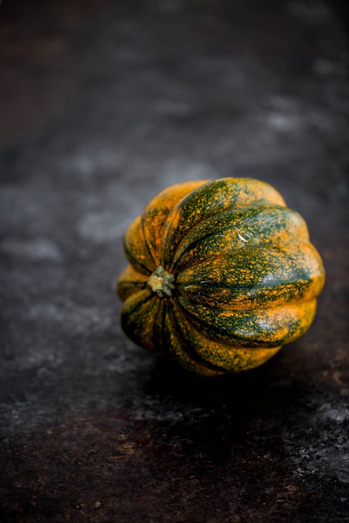 photo of a whole acorn squash on dark background