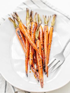 whole roasted carrots on a white plate