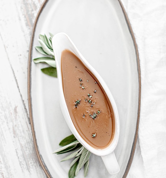 turkey gravy with sage in a white gravy boat