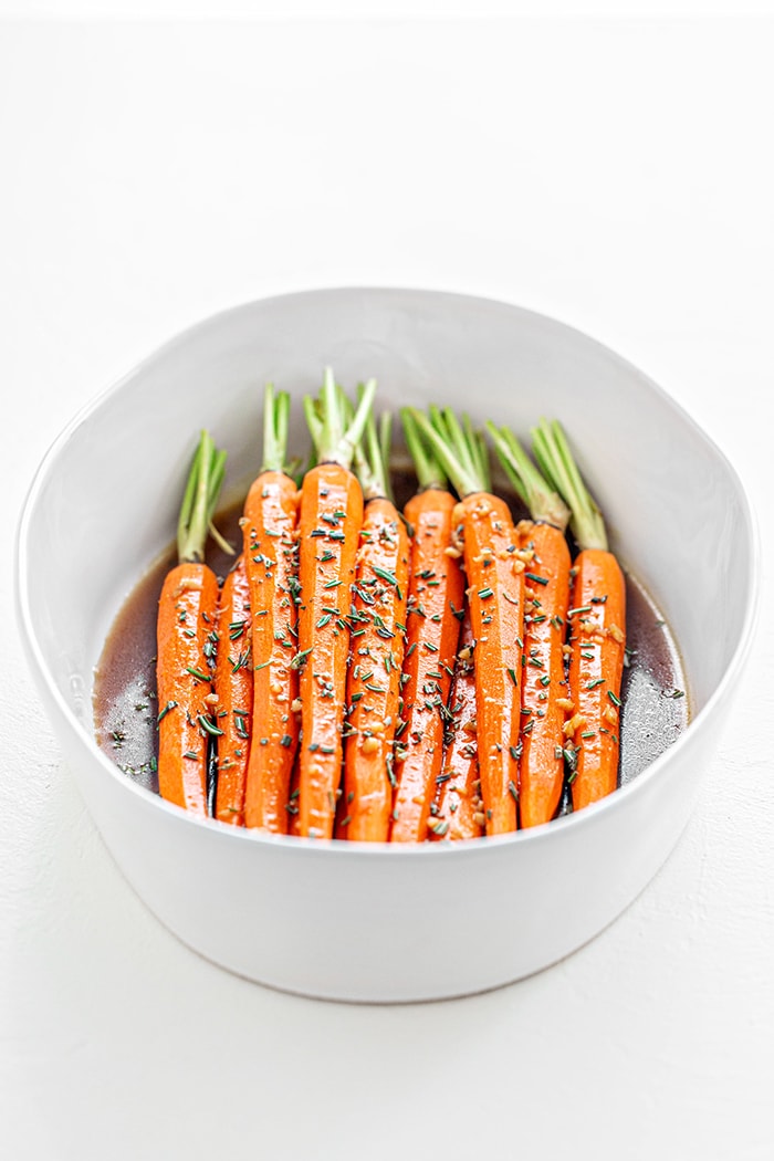 whole balsamic carrots in a white bowl