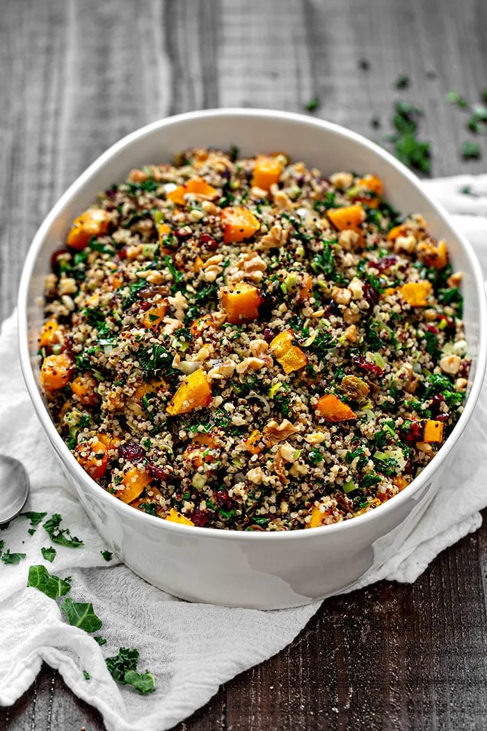 photo of a casserole dish of quinoa stuffing (gluten free stuffing recipe) on a wooden table with a serving spoon