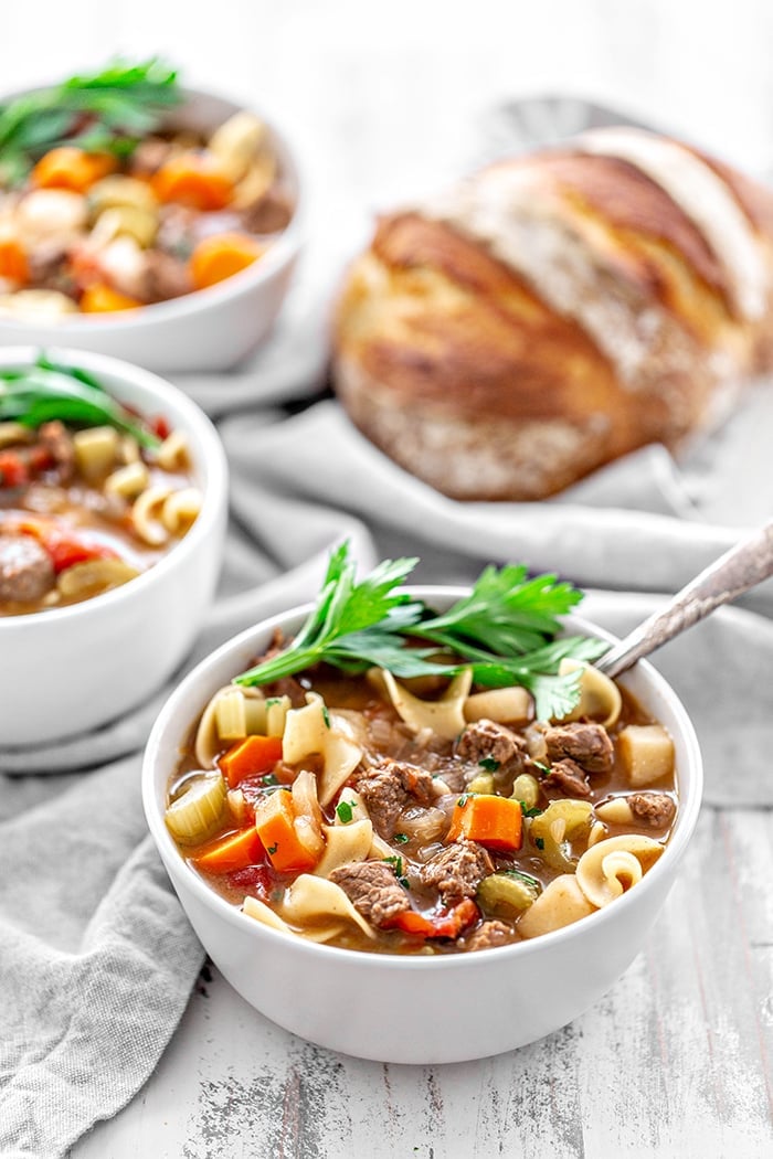 white bowls of beef and noodle soup