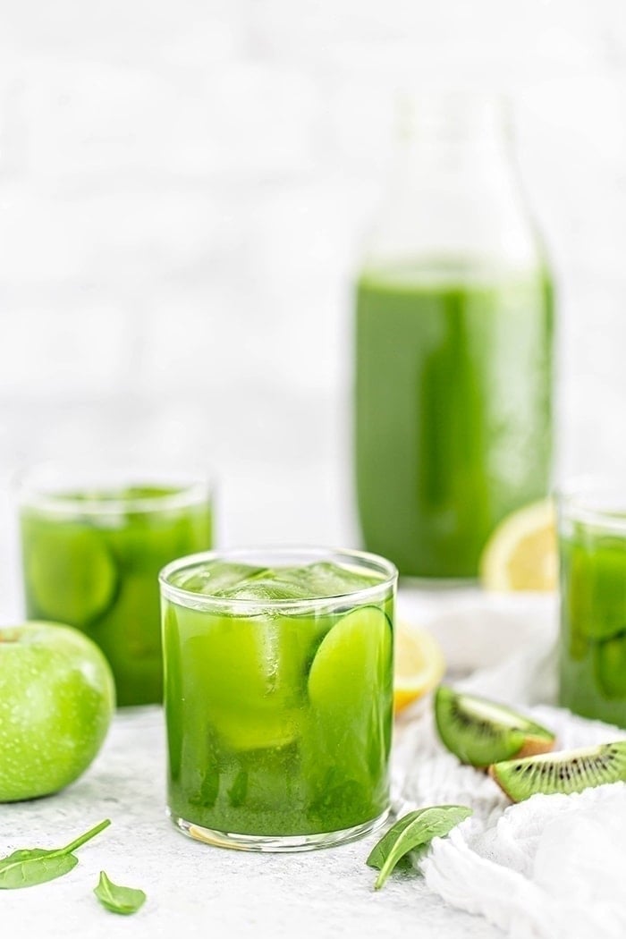 3 glasses of green juice with apples, spinach, lemon, cucumber, and kiwi