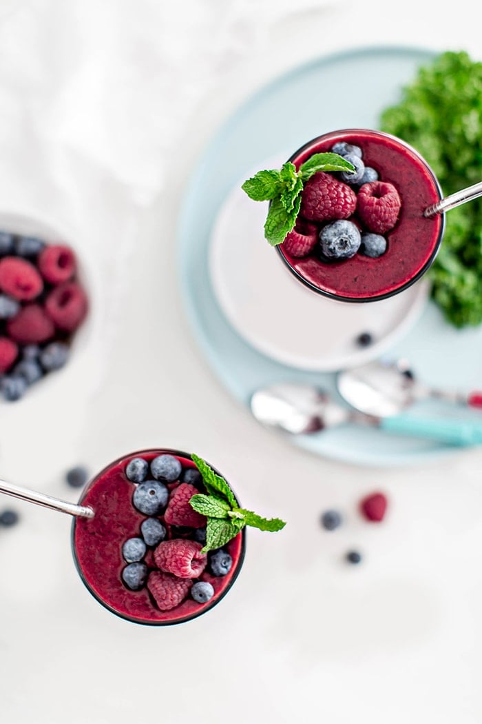 glass with berry mango kale smoothie and straw