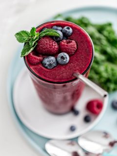 glass with berry mango kale smoothie and straw