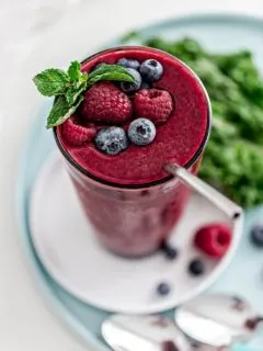 glass with berry mango kale smoothie and straw