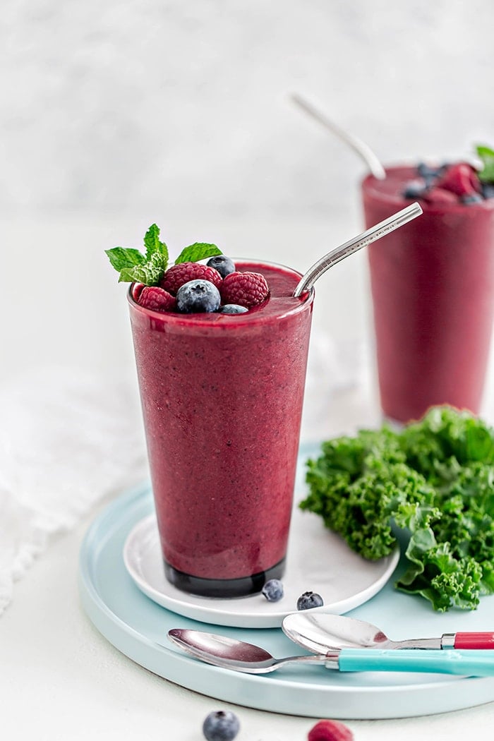 glass with berry mango kale smoothie and straw