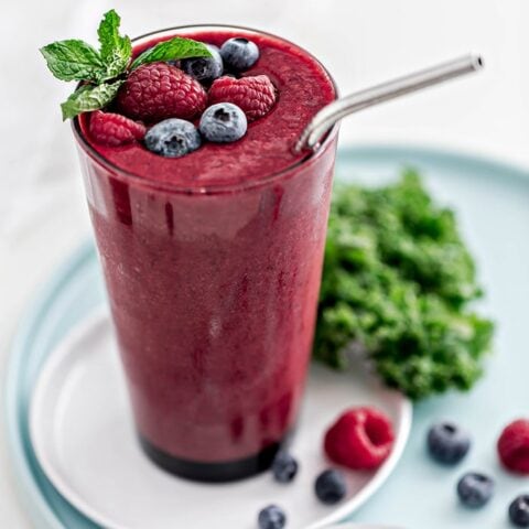 glass with berry mango kale smoothie and straw