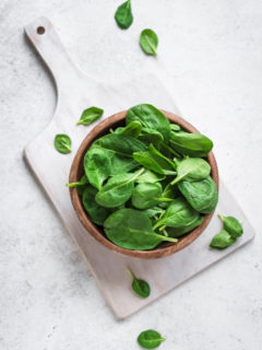 bowl of spinach on top of a cutting board