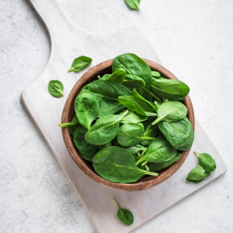 bowl of spinach on top of a cutting board