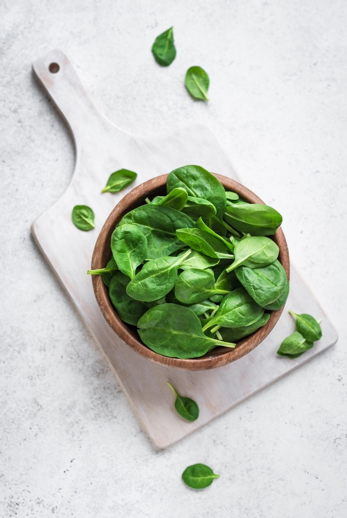 bowl of spinach on top of a cutting board