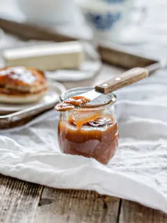 wooden table set with breakfast and a jar of pear butter