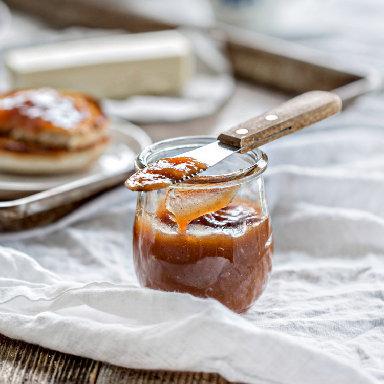 wooden table set with breakfast and a jar of pear butter