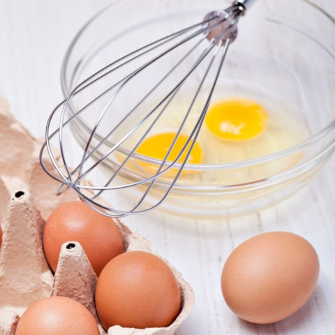 cracked eggs in a bowl with whisk