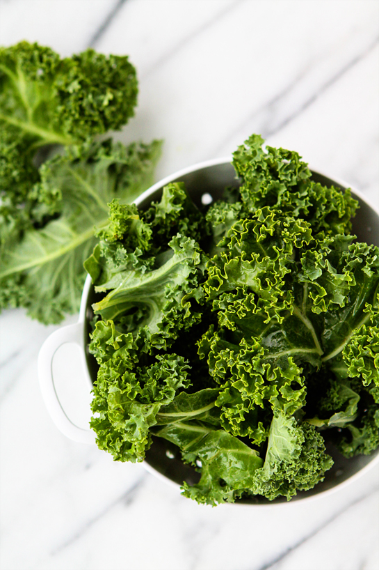 a bowl of kale leaves on a white background