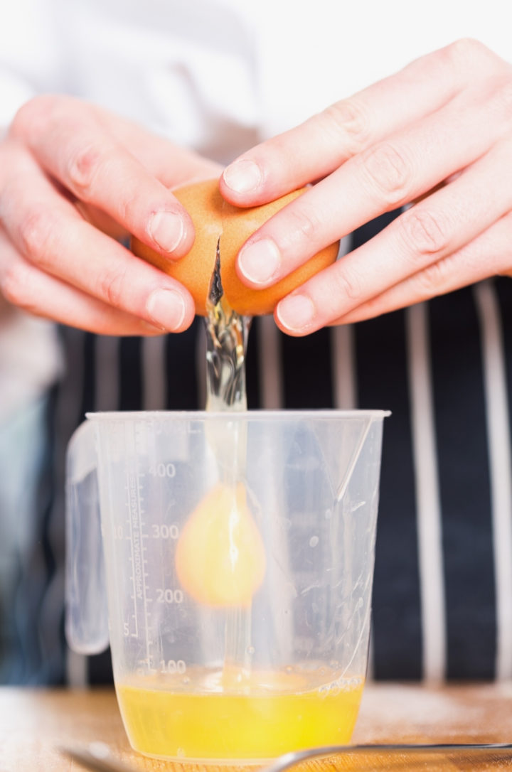 cracking an egg in a measuring cup