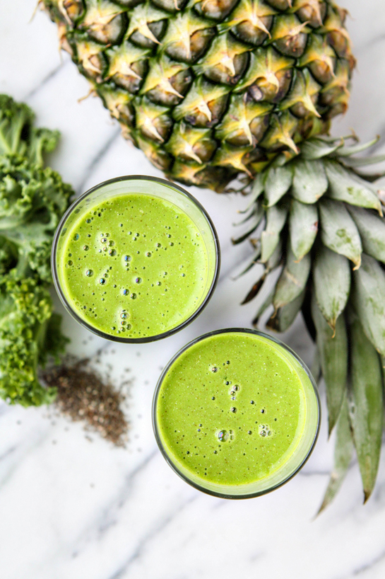 green smoothie in a glass with pineapple and kale