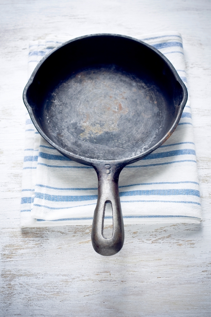 rusted cast iron pan on top of a folded towel on a white table
