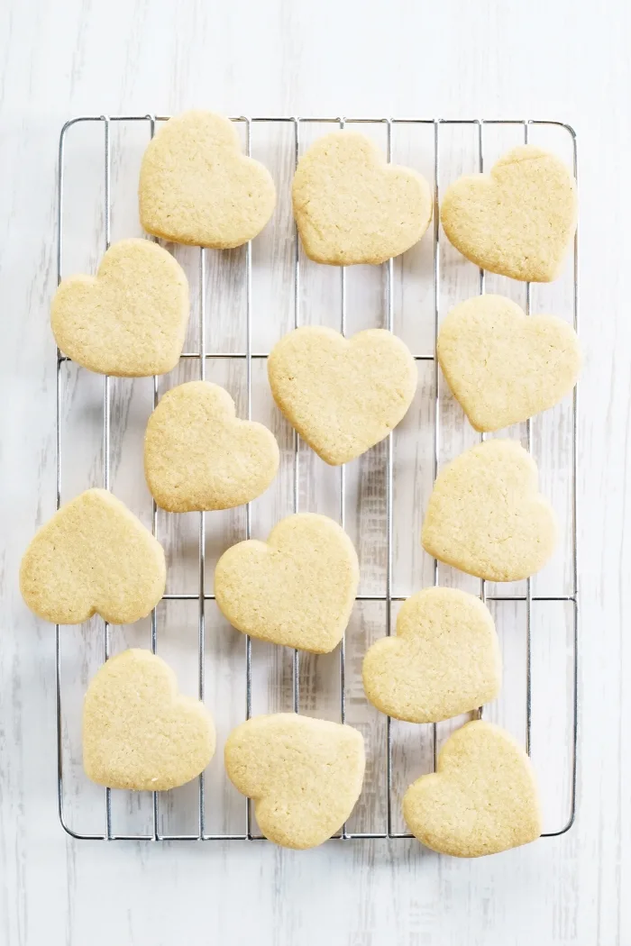 wire rack with heart shaped cut out cookies on a white background