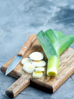 leeks on a wooden cutting board with a knife