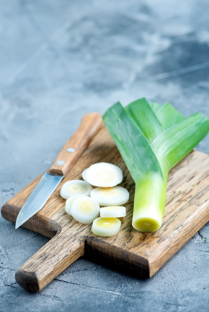 leeks on a wooden cutting board with a knife