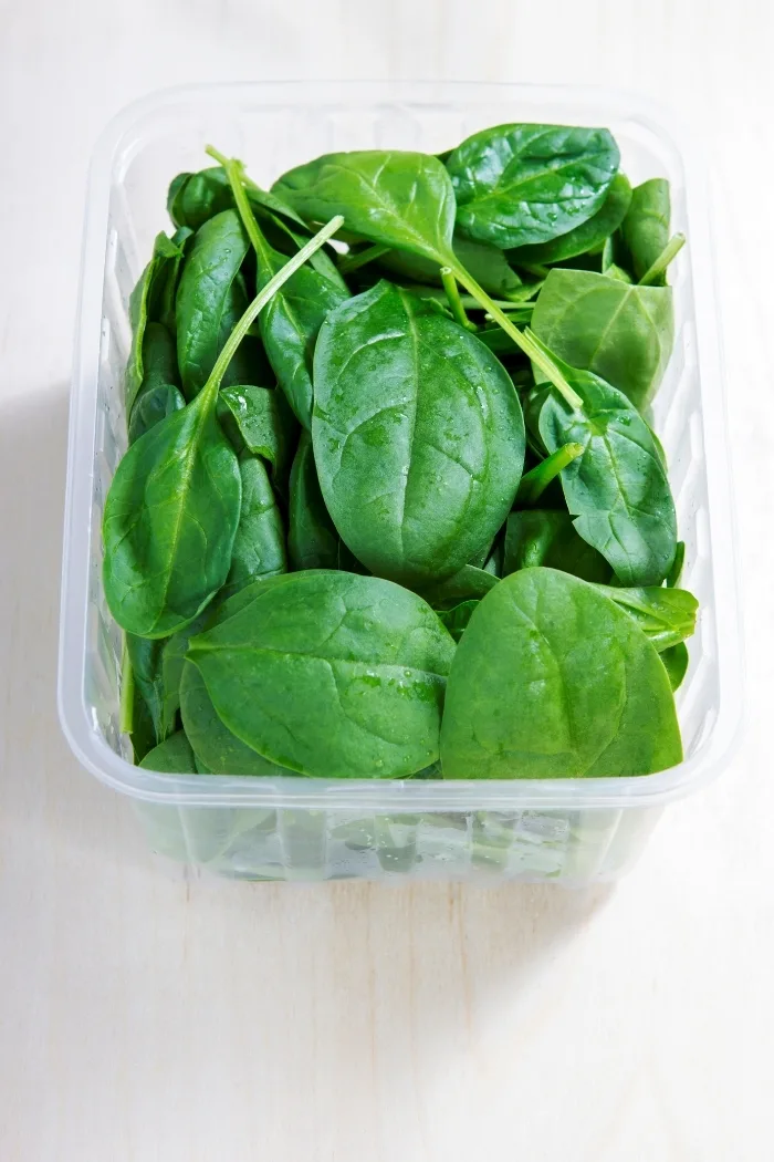plastic container with baby spinach leaves