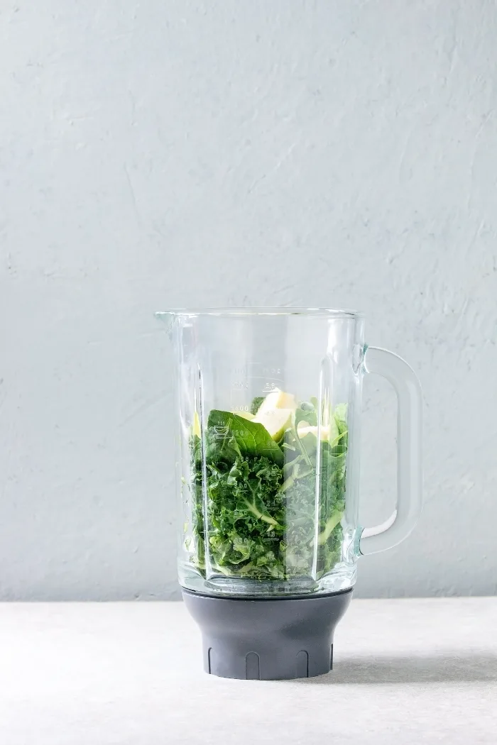 blender with spinach, fruit, and other greens to make a green smoothie