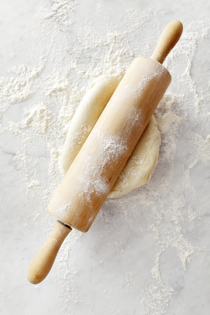 rolling pin with dough on a marble surface