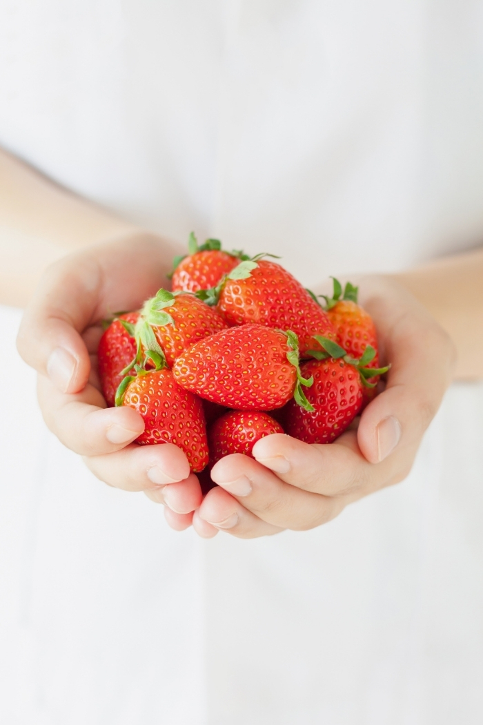 child holding fresh strawberries in hands for strawberry dessert recipes