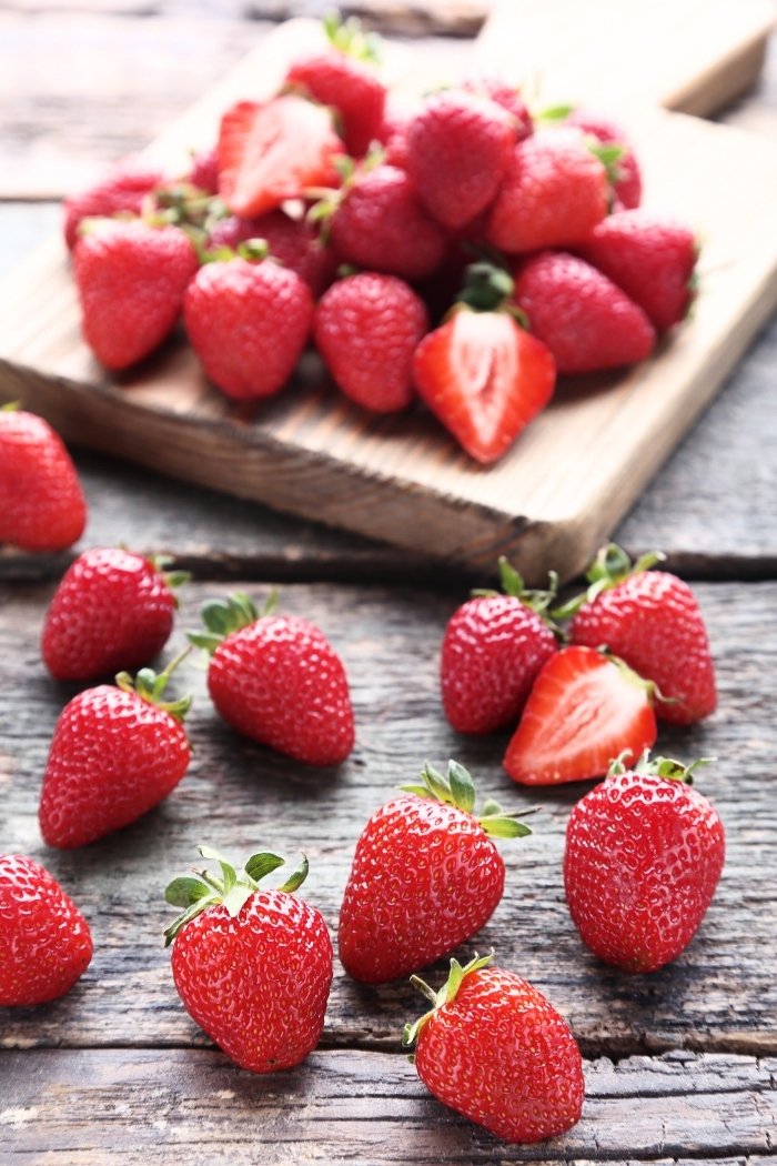 strawberries on a wooden cutting board on a table