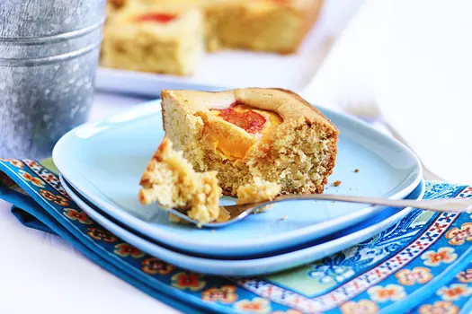 close up of a slice of peach cake on a blue plate with a fork