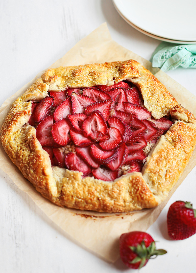 strawberry galette on parchment paper next to plates