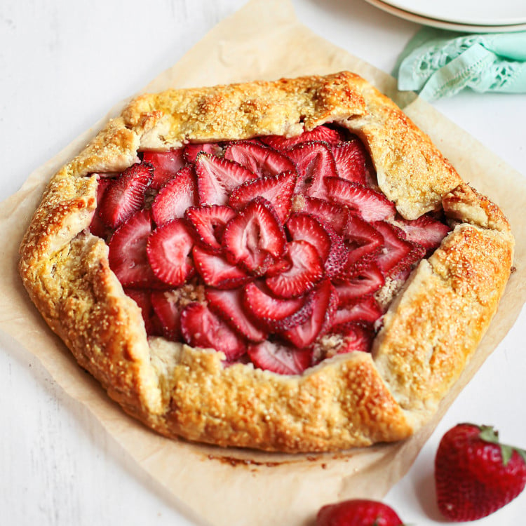 strawberry galette on parchment paper next to plates