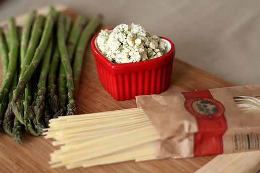 Ingredients needed to make gorgonzola pasta sauce on a wood cutting board.