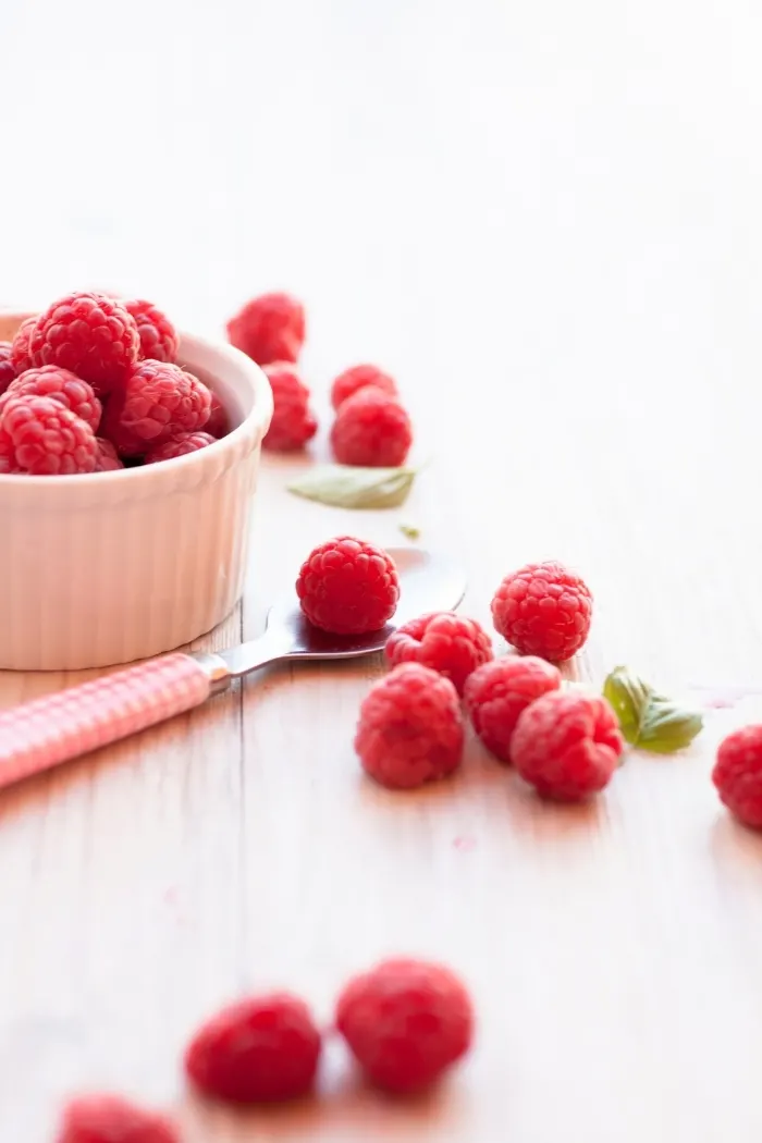 photo of raspberry curd ingredients: fresh raspberries in a ramekin on a wooden surface 
