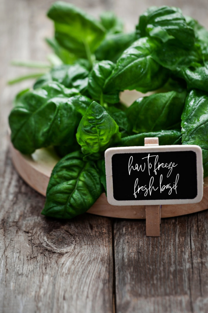 fresh basil leaves on a wooden cutting board with a sign that says how to freeze basil