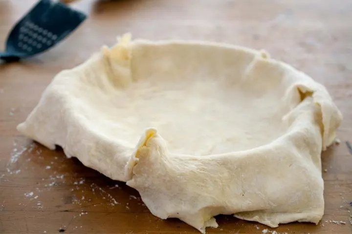 all butter crust dough being transferred to a pie plate