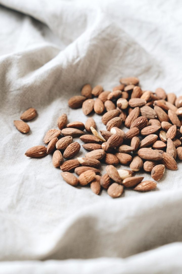 whole almonds on a dish towel to use to make this recipe for almond butter cookies