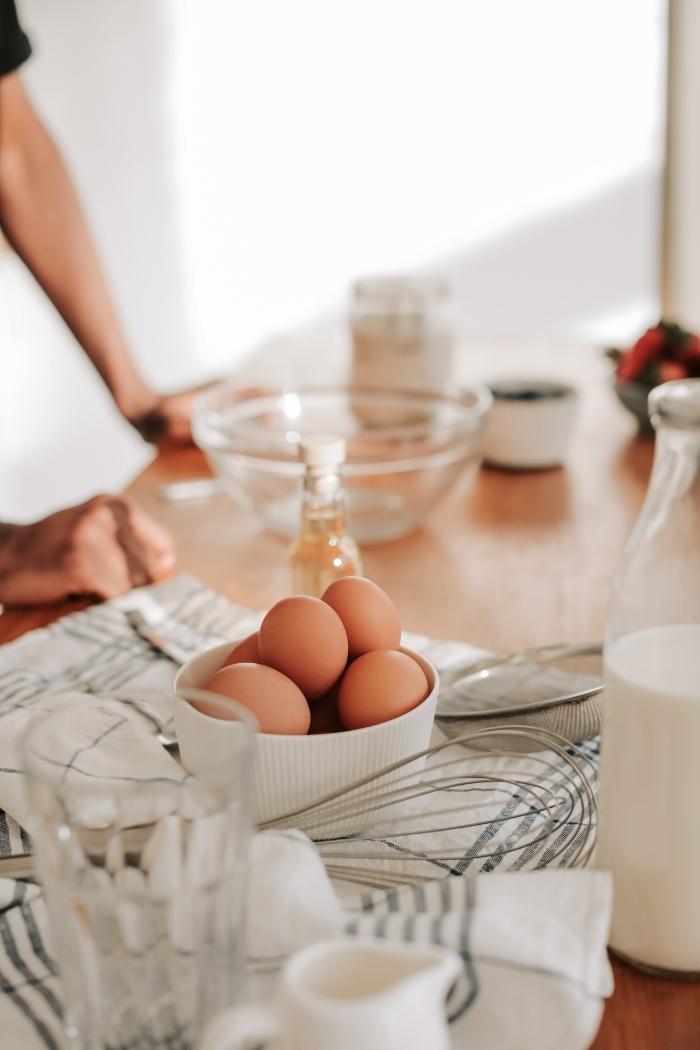 brown eggs in a white bowl on the counter with baking supplies