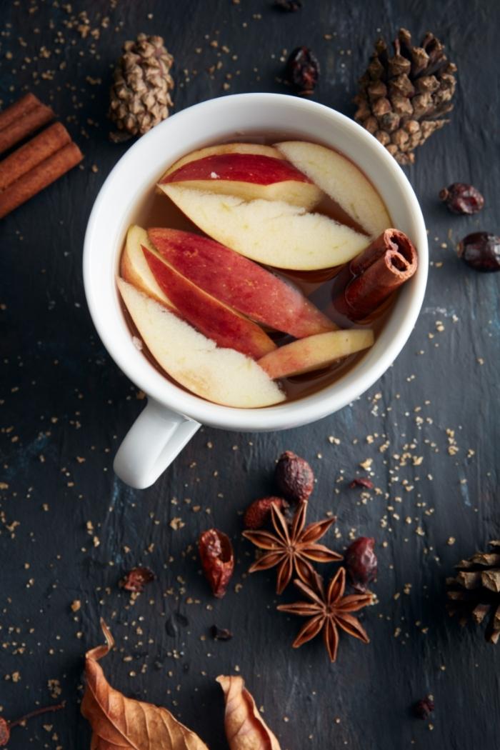 mugs of hot apple cider with apple slices and cinnamon stick