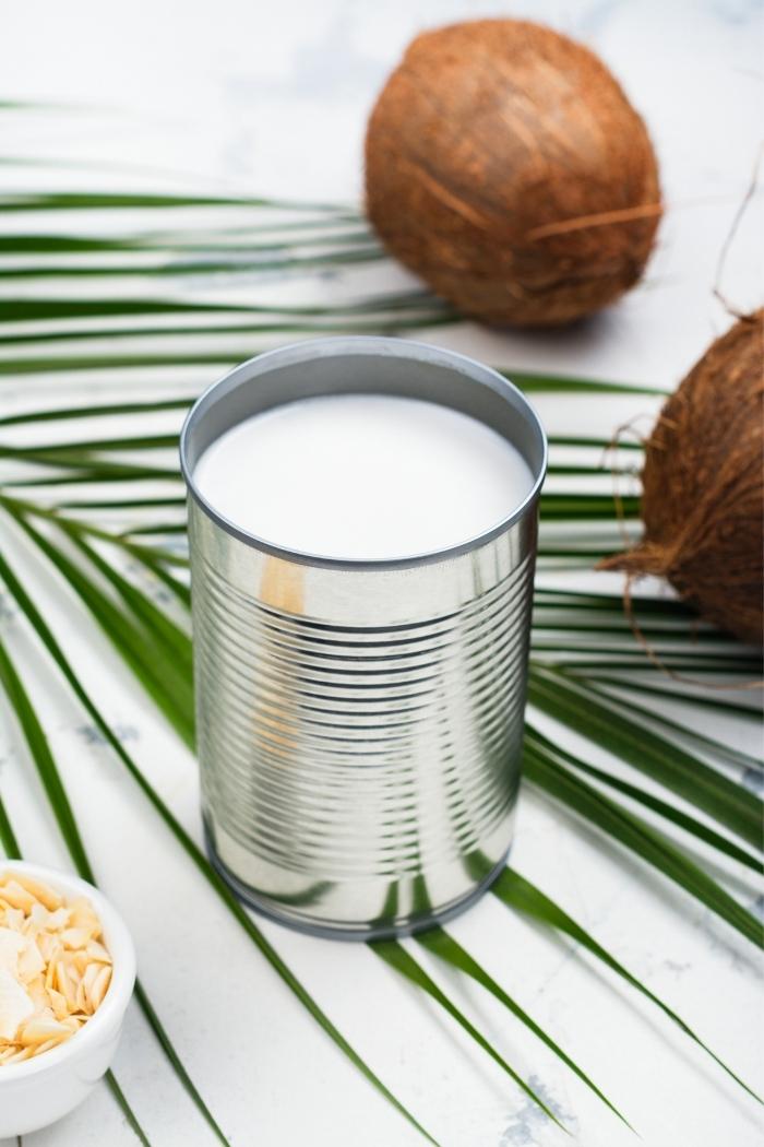 coconut milk in a can with coconuts in the background