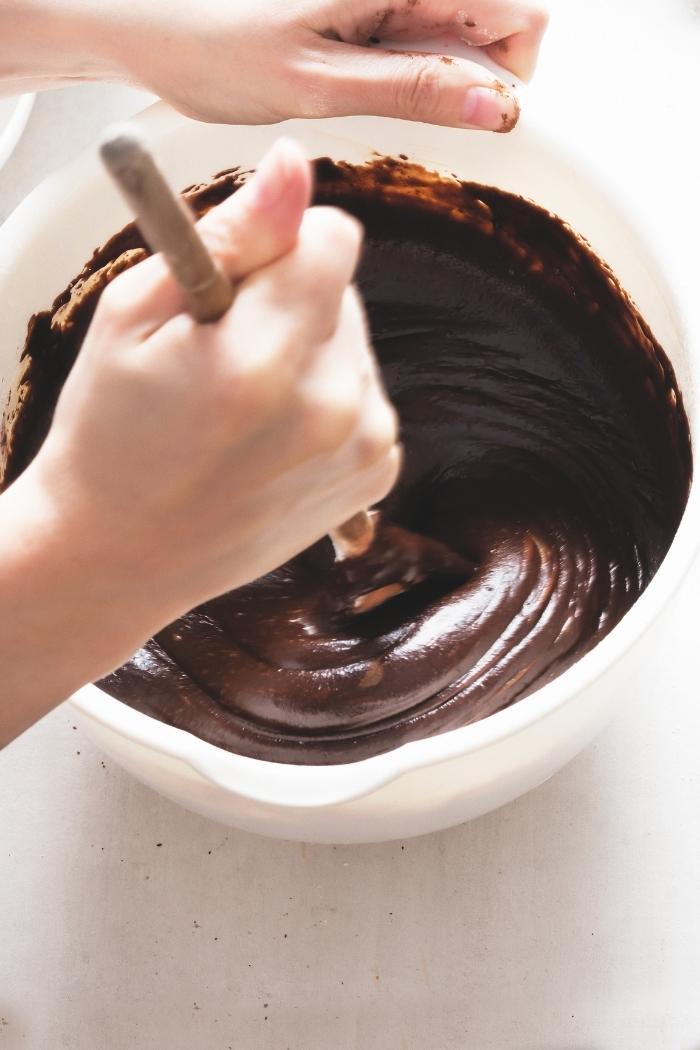 woman stirring batter for homemade brownies with a wooden spoon